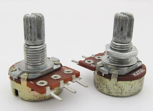A pair of three-pin potentiometers. The pins are laid in a straight line horizontally.