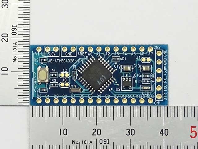 A blue circuit board, with an ATMega328P on it. The silkscreen says it is an AE-ATMEGA328-MINI. Pins D0, D1, ... D10 run along the bottom.