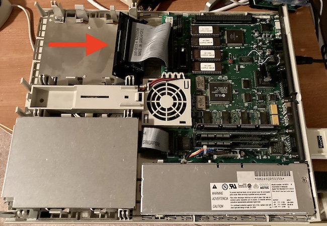 BlueSCSI board (indicated with a red arrow) is loaded into the hard drive bay of a Macintosh LC. You can also see a bunch of bodge wires and corrosion left behind from the "rescue" job that I did on this machine a few years ago.
