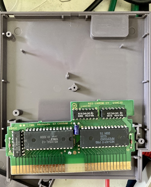 The inside of a Casino Kid cartridge. The main PCB is NES-UNROM-09, and it is equipped with an OKI M5165AL-12 RAM chip for character RAM, a Nintendo-branded CIC chip, an NES-KP-0 mask PRG ROM, a 74HC32 OR-gate, and a 74HC161 binary counter.