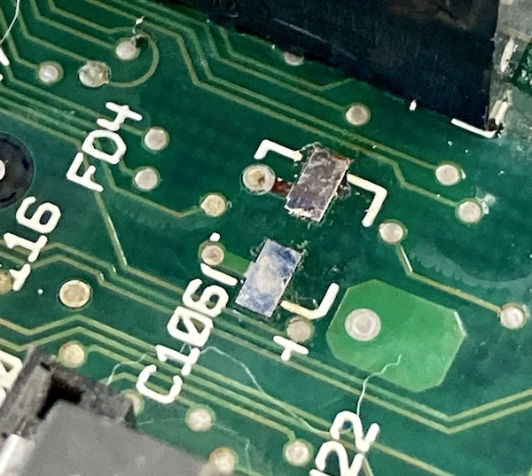 The C106 pads are exposed. You can see that the trace from the negative terminal is also exposed, with its green solder mask torn up.