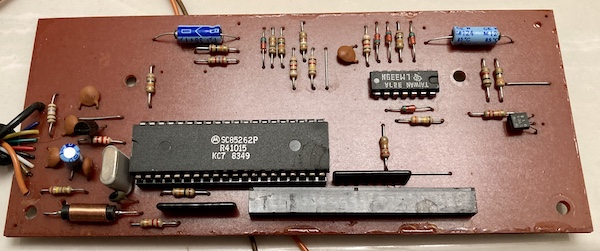 The PCB inside the RF-shielded "backpack" of the keyboard. It has a large DIP (socketed!) and some passives, several diodes, as well as a clock crystal and two transistors. The black connector which accepts to the tail of the membrane is at the south end of the picture.