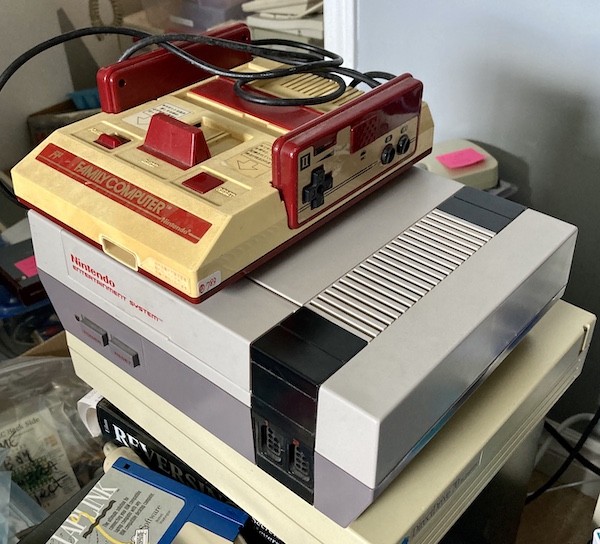 A Famicom is sitting on top of an American front-loading NES, which is a spoiled Western brat and doesn't like loading cartridges.