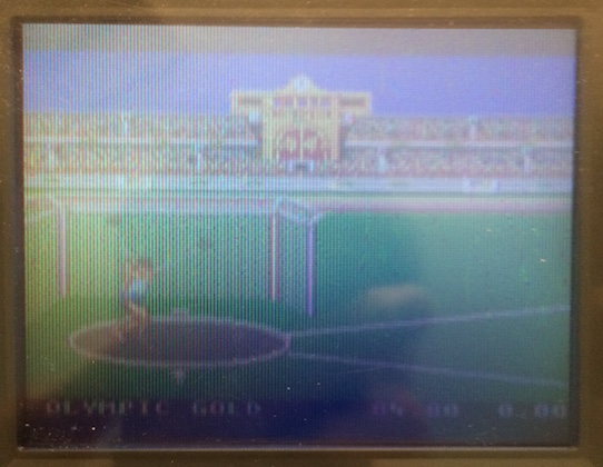 The Game Gear is displaying a little Caucasian pixel man trying to chuck a shot-put in an imagined version of a future Olympics that had happened decades prior to this shot being taken.
