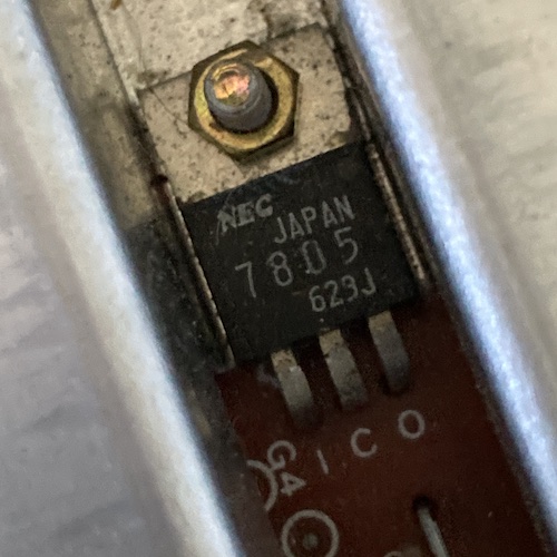 An NEC 7805 voltage regulator bolted to the heat sink of the Mark III. It says NEC JAPAN 7805 623J. Beneath it, the pins from left to right read I C O on the motherboard.