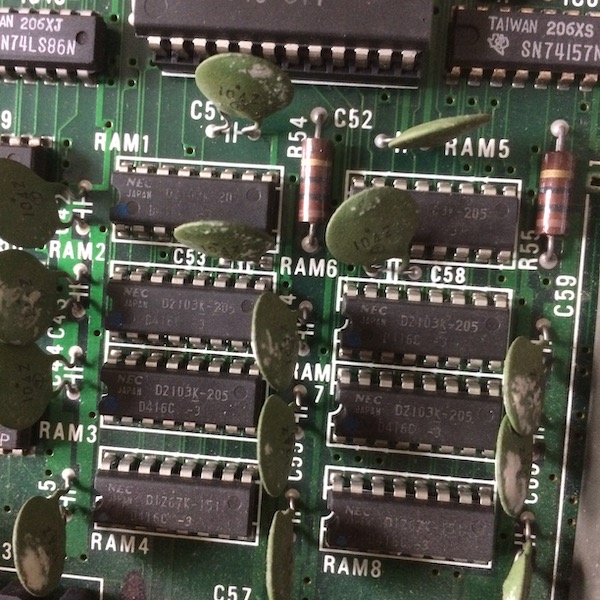 The PC-6001's RAM. There are eight of them, numbered from RAM1 to RAM8. They are NEC 416C parts. Each one seems to have a weird green ceramic disc capacitor for filtering.