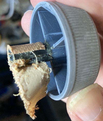 The plastic knob for the paper-feed mechanism. It has had many years of grease, grime, failed repairs and tape on it, and now it has a huge crack all the way up the shaft. I should trim my fingernails.