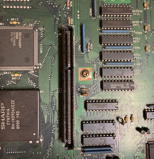 The card cage connector on the motherboard. It has some white powdery substance that is likely dried-out swamp water. There are a worrying number of Fujitsu fast-logic buffers nearby.