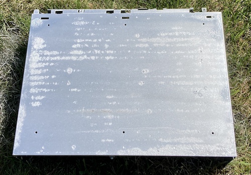 The bottom of the case after Tremclad. Most of it is shiny, but you can see the parts where the rust used to be haven't been filled in completely. In the background is my horrid lawn, which is in even worse condition thanks to some moron hitting it with spray paint.