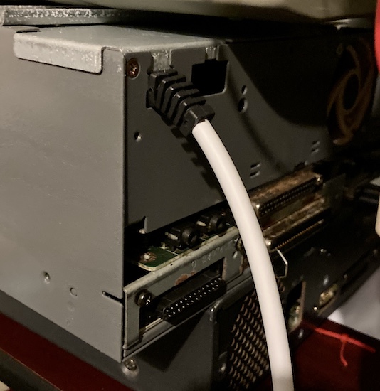 The strain relief and cord installed into the back of the power supply, which is itself installed into the computer. A mysterious other computer lies underneath. Will it Drive you to Terror?