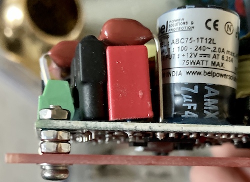 The AC-DC PCB is mounted above the red power supply PCB. Each standoff is a machine screw, two washers (one lock), two nuts, and then another nut on top of the PCB holding it down. There's a little bit of thread still peeking out the top on the screws.