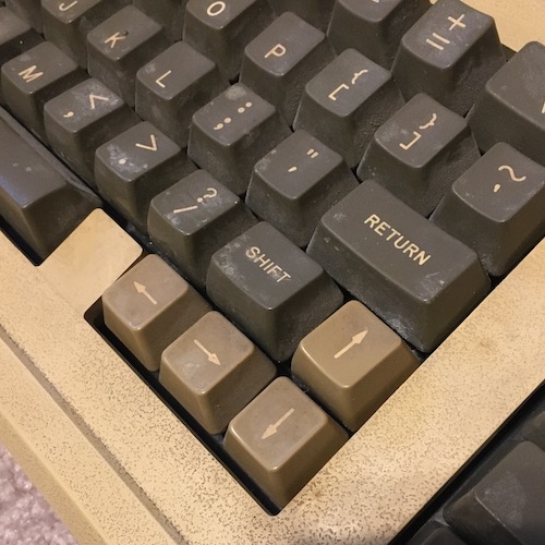 The cursor keys are in a dumb arrangement. Up and down are on the far right, and then to the left of them are left and right. The tilde key is above Return.