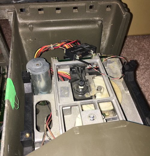 The internal belt-driven floppy drive and its wiring is exposed now that the RF shield is removed. It has another expensive-looking aluminum frame, several bizarre cables, and a very large motor.