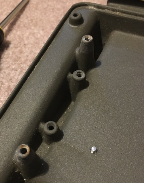 The computer's underbody, specifically the keyboard tray, made of cast aluminum. Threaded holes are present to mount the keyboard.