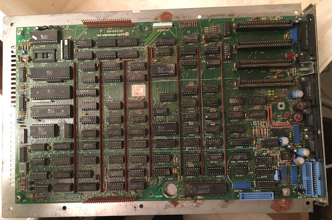 The logic board has been removed from the case and placed precariously on a utility sink.