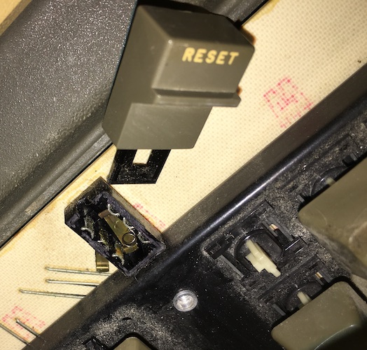 The reset switch at the top of the keyboard has fallen apart. There are some metal pieces, tiny springs, and the switch itself.