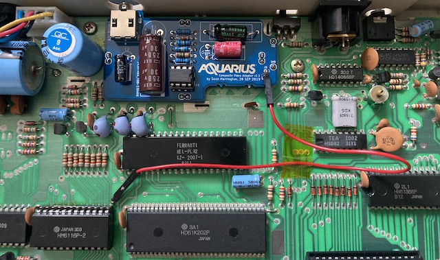 The AV mod has been slammed onto the motherboard and soldered down, with a red jumper wire leading between the +5V source and sink.