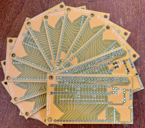 The completed v0.1 boards, in yellow, fanned out on my rotten kitchen table.