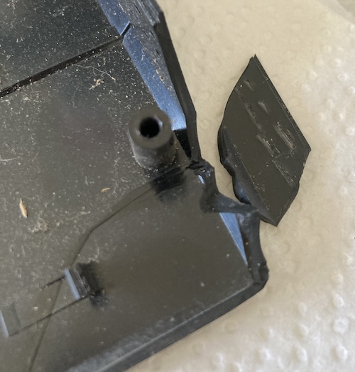 A repaired chunk of plastic on the top lid is having another chunk glued onto it.