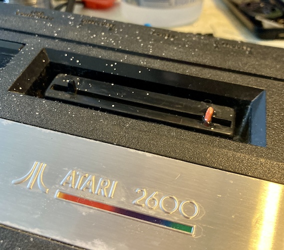 A bright orange ejector pin sits in the cartridge slot.