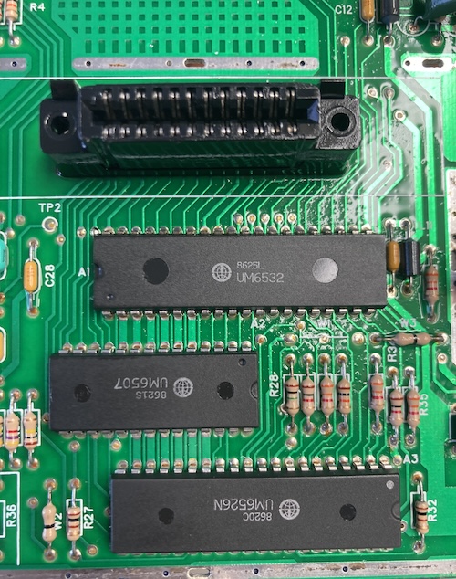 The motherboard has been washed, showing three chips: a UM6532, UM6507, and UM6526. All of them have 1986 date codes. The cartridge connector shows some concerning black spots.