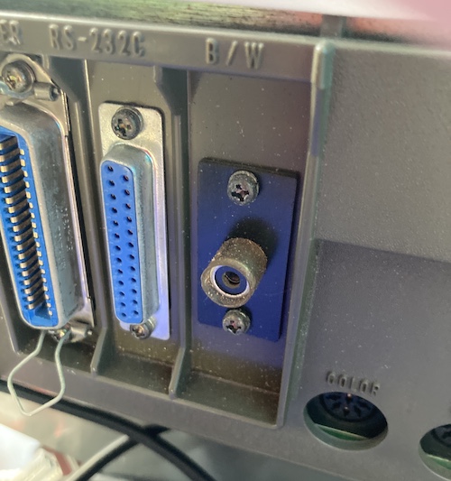 The "B/W" RCA jack is covered in some kind of rubber shrink-wrap tubing. Next to it, you can see a 25-pin RS-232C port and a large Centronics style parallel port for printing