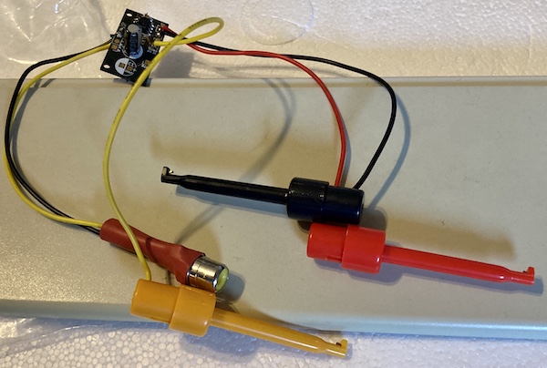 My trashy composite-video probe. It's a purple Famicom composite amplifier board, a yellow RCA jack, and red, yellow, and black test hooks.