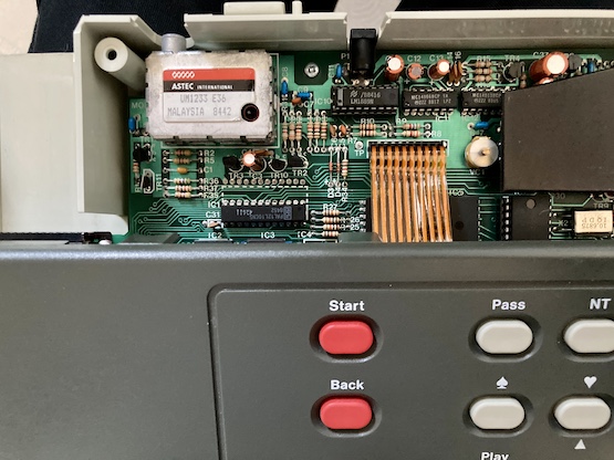 The top panel is pulled back, showing the ribbon cable connection into the motherboard. An Astec UM1233 RF modulator is visible.