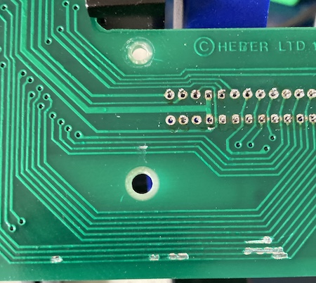 The pre-existing damage to the solder mask on the underside of the board, probably caused from forking cartridges in and out of the machine. I put some new solder mask paint on here and called it a day.