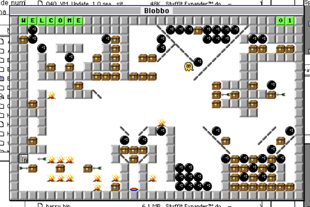 A game of Blobbo is in progress. A bunch of lethal bowling balls are sliding out of a vicious trap next to a yellow blobby guy, exposing a treasure chest to be picked up.