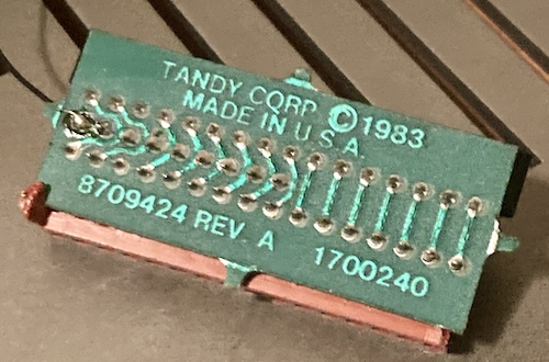 The bottom of the little bodge board, stating Tandy Corp Copyright 1983, Made in U.S.A., 8709424 Rev. A, 1700240. I just now noticed some bad solder joints on the edge. Is this what was wrong with the membrane the whole time? Did I waste all this money and effort for some stinkin' solder joints on a badly designed adapter?