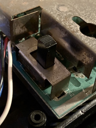 The ColecoVision's power switch. You can see that hand oils and dust have built up on the metal shielding of the switch over the years, slightly eroding the finish. This machine was heavily used. Although I didn't photograph it, the case plastic around the power switch has friction wear as well.