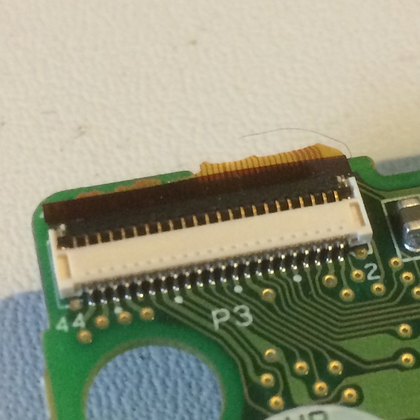 A torn film ribbon cable hangs out of its connector
