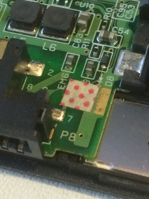 The water-damage sticker, showing pink dots indicating water exposure
