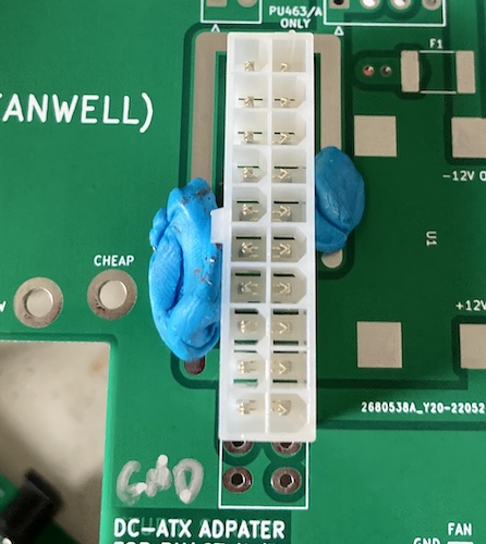 The 20-pin connector is fitted into a 24-pin footprint. Some globs of blue poster putty are holding it up to prepare for soldering.