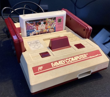 The Famicom, sitting on my desk chair. Momotaro Densetsu is loaded into the cartridge slot.