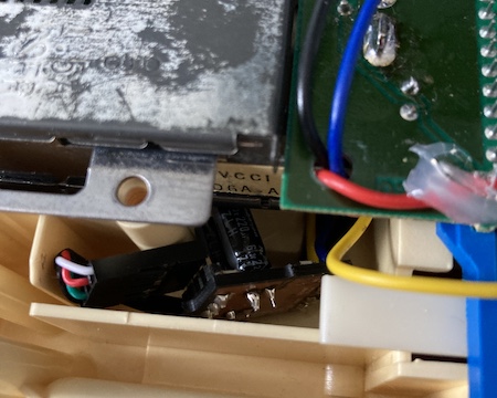 The board is wedged into the corner of the case; you can see a yellow wire and some globs of hot glue in the foreground.
