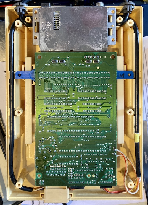 The Famicom's bottom cover is opened, revealing the underside of the motherboard.