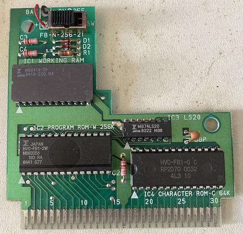 The Family BASIC cartridge PCB is exposed. It has three big chips: IC1 Working RAM, IC2 Program ROM-W 256K, and IC4 Character ROM-C 64K. There's a smaller fourth chip, an MB74LS20, as well, denoted as IC3.