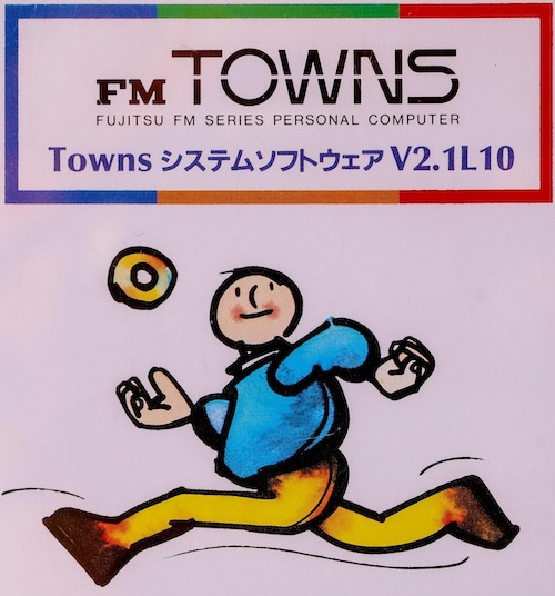 A sketchy, crayon like doodle of a bald dude throwing a CD in the air as he runs. The label says that it is FM Towns System Software V2.1L10.