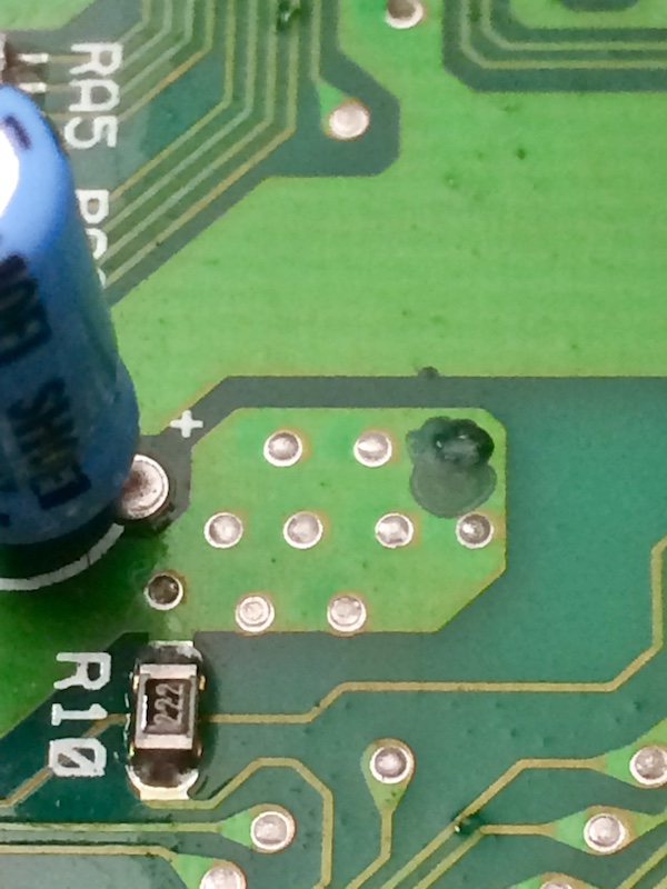 Weird dark green blob covering a test point. I don't know what happened here, but it feels like it might be solder resist repair. It's very hard to the touch.