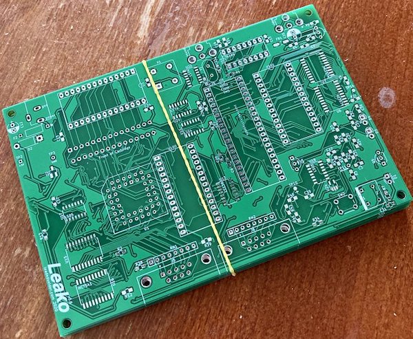 Leako v0.6 board, before being assembled. It's green and has through-hole RAM footprints where the SMD RAM footprints used to be. It is a stack of boards held together by a rubber band.