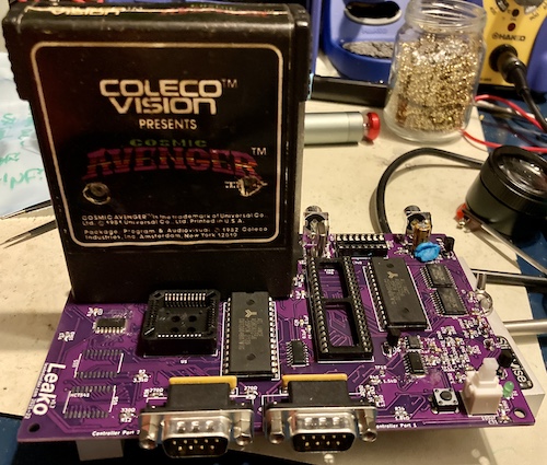 Partially assembled, but with nothing socketed and no '541s installed. A "Cosmic Avenger" cartridge is inserted into the slot. Some blue tack is wedged into the 220µF capacitor in the corner.