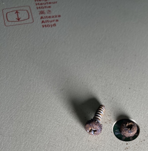 One of the very rusty fine-thread screws holding in the power supply. Next to it, a very rusty coarse-thread body screw.