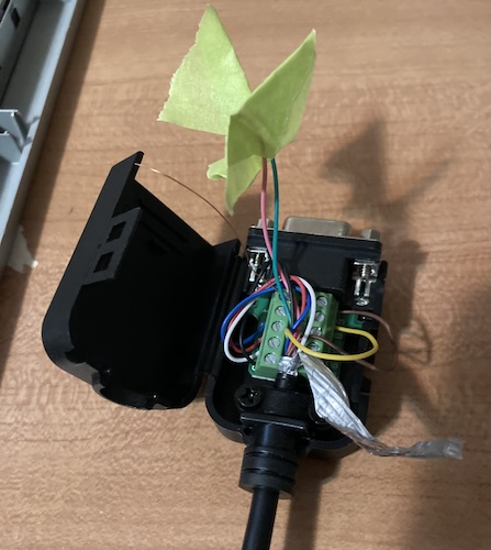 A homemade adapter. A screw-terminal breakout box has a bunch of wires in it coming from a DIN cable. Some of the unused DIN wires are insulated from shorting with green masking tape. The braided shield part of the cable is dangling loose in space.