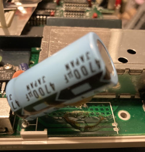 A 4700µF capacitor is wobbly. There are cracked remnants of glue underneath it.