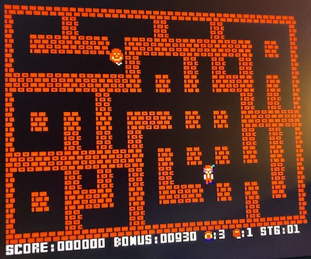 The first stage of Bomberman. Bomberman (lower right) is in a randomly generated maze. A red balloon is menacing him from the top left.