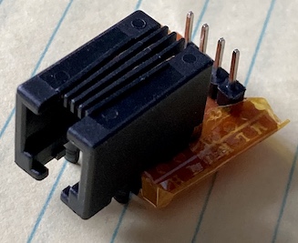 The little breakout board I made for this. It is a 4p4c jack at a slight angle on some jaggedly-cut protoboard, wrapped in Kapton tape. A 0.1" pin header sticks out of the top for interfacing to the Arduino board.