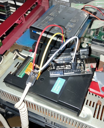 The 4p4c breakout hanging off the end of an Arduino clone, with a giant beige handset cable dangling out of it. The computer is wide open and parts are scattered everywhere.