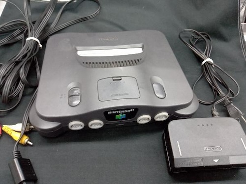 The auction photo, showing a Nintendo 64, some bundled cables, and a power supply, against a featureless black blanket.